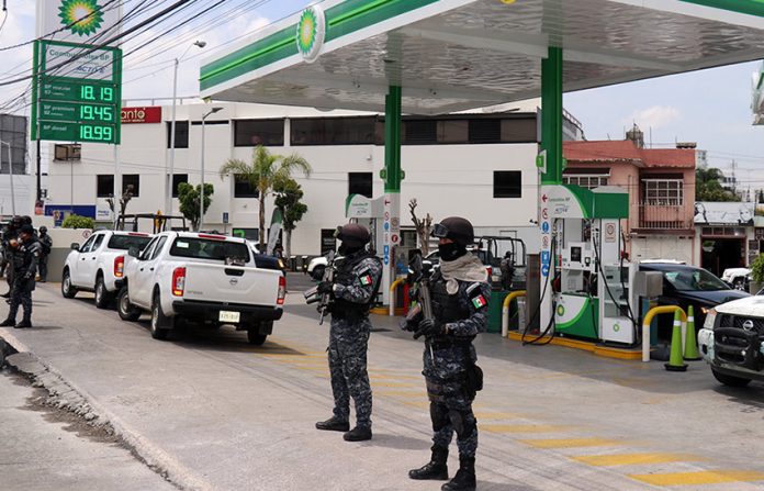 Police stand guard at a BP gas station in Puebla.