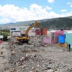 An excavator demolishes one of the houses built for hurricane victims.