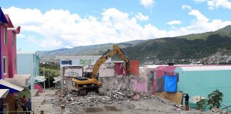 An excavator demolishes one of the houses built for hurricane victims.