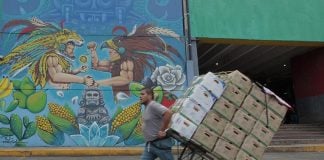 A man pulls a produce cart past one of the existing murals at the Mexico City market.