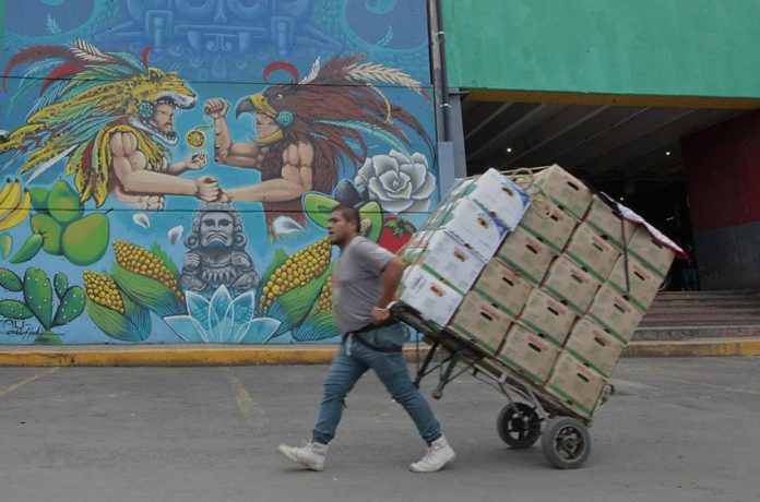 A man pulls a produce cart past one of the existing murals at the Mexico City market.