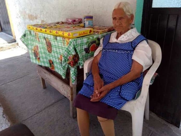 Jalisco's oldest woman sells candy on the sidewalk outside her home.