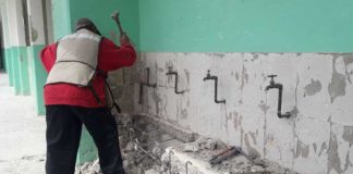 A worker carries out repairs at a school damaged by earthquakes.