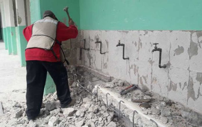 A worker carries out repairs at a school damaged by earthquakes.