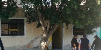 Investigators outside the house where bodies were buried.