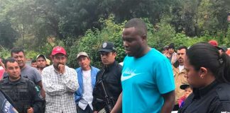 Police look on as Colombian citizen Lozano, accused of extortion, speaks with residents. They lynched him shortly after.