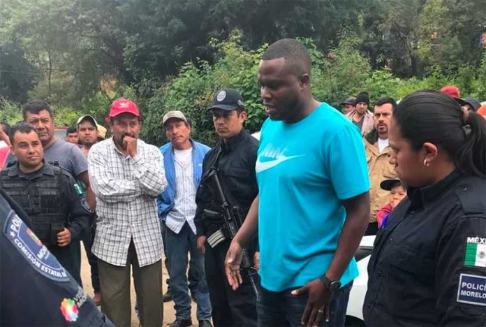Police look on as Colombian citizen Lozano, accused of extortion, speaks with residents. They lynched him shortly after.