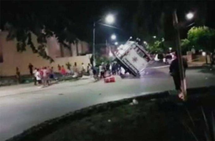 Residents push over a mobile police unit in Playa del Carmen last night.