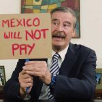 Vicente Fox holds a sign bearing a message for Trump regarding the border wall.