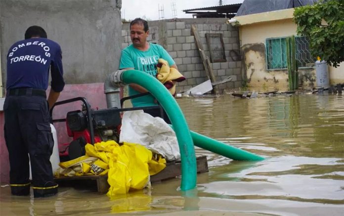 A Torreón firefighter mans a pump to remove floodwaters.