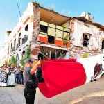 Against a backdrop of earthquake damage, Juchitán flag is lowered to half mast to mark the quake's anniversary.