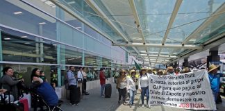 Protesters carry a banner calling for payment of money owed to communal landowners.