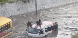 Children wait on the roof of a stranded transit van.