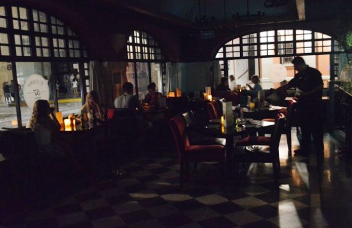 Patrons dine by candlelight in a Mérida restaurant during electricity rates protest.