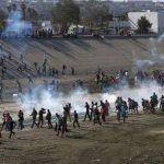 Migrants rush the border yesterday in Tijuana.