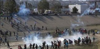 Migrants rush the border yesterday in Tijuana.