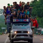 Migrants hang off a truck en route to Mexico City.
