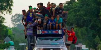 Migrants hang off a truck en route to Mexico City.