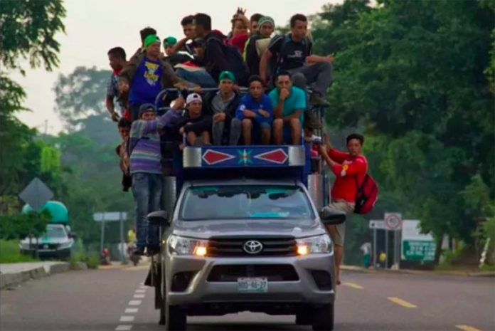 Migrants hang off a truck en route to Mexico City.