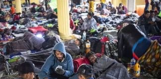 Migrants bed down, play cards in Tijuana.