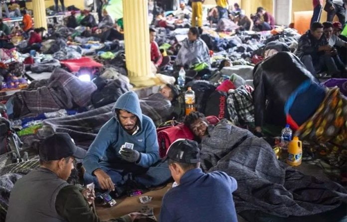 Migrants bed down, play cards in Tijuana.