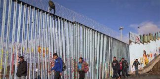 Migrants at the border fence near Tijuana.