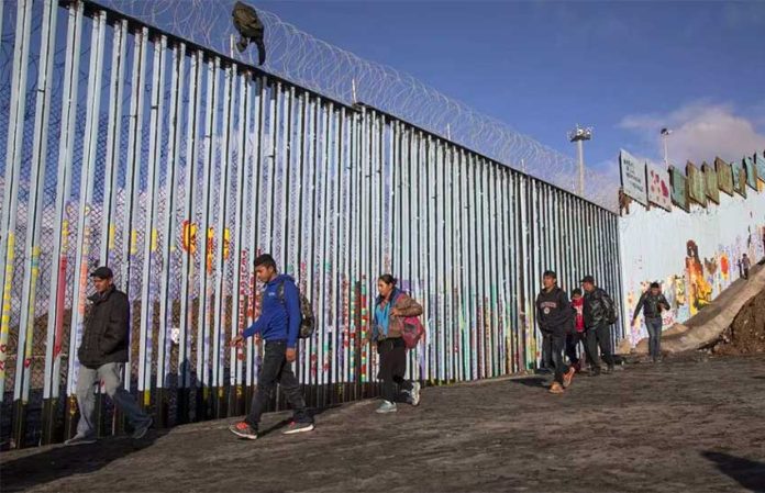 Migrants at the border fence near Tijuana.