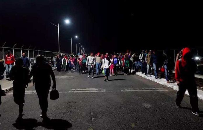 Migrants cross a bridge this morning to enter Mexico.