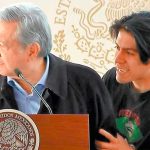 The young man who breached AMLO's security stands with the president on the stage.