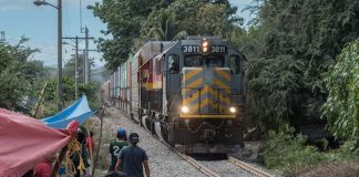 A train rolls in Michoacán but teachers maintain a vigil to the side of the tracks.
