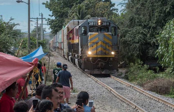 A train rolls in Michoacán but teachers maintain a vigil to the side of the tracks.