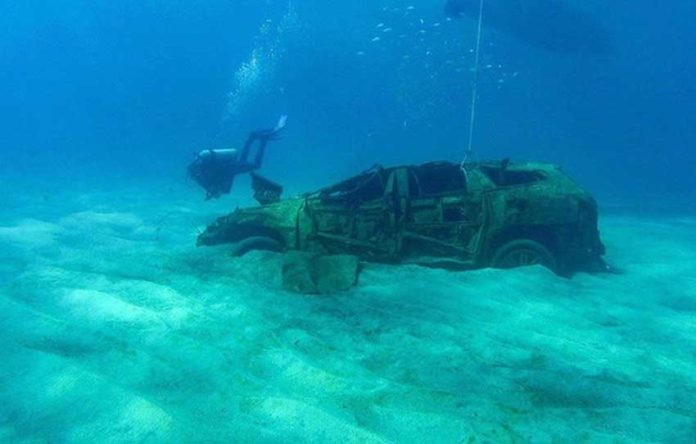 A diver swims near one of the eight vehicles at the bottom of Cabo San Lucas bay.