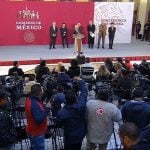 Backed by other government officials, the president speaks at his daily session with the press.