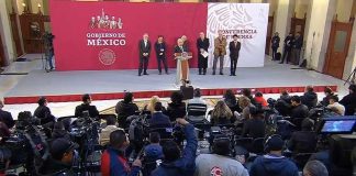 Backed by other government officials, the president speaks at his daily session with the press.