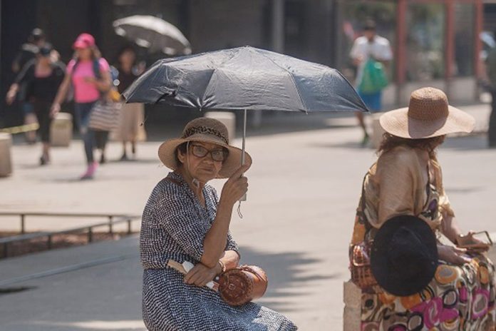A woman shades herself from the sun in Mexico City, where more hot weather is in the forecast.