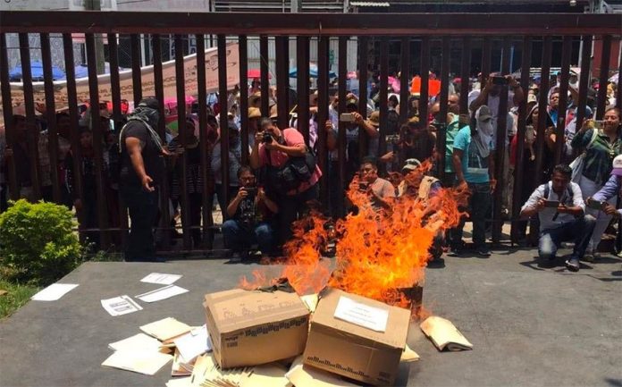 Guerrero teachers burn documents while vandalizing government buildings.