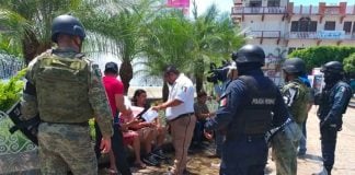 Security forces stand watch as an immigration agent speaks with migrants in Chiapas.