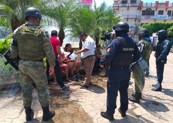 Security forces stand watch as an immigration agent speaks with migrants in Chiapas.