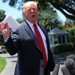 Trump holds up the agreement for reporters on Tuesday.