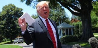 Trump holds up the agreement for reporters on Tuesday.