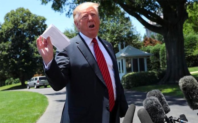 Trump holds up the agreement for reporters on Tuesday.