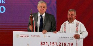 AMLO presents a check to the mayor of Metlatónoc, proceeds of an auction of narco-real estate.