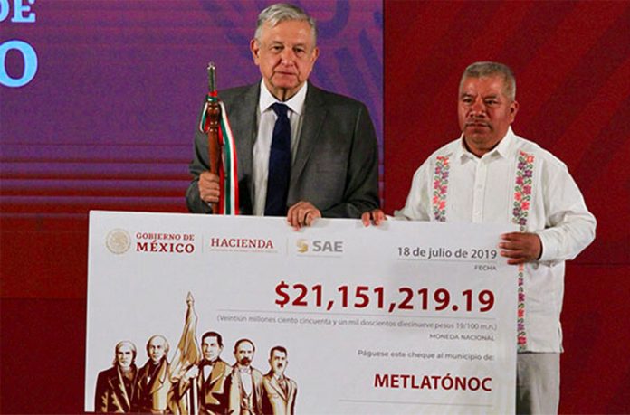 AMLO presents a check to the mayor of Metlatónoc, proceeds of an auction of narco-real estate.