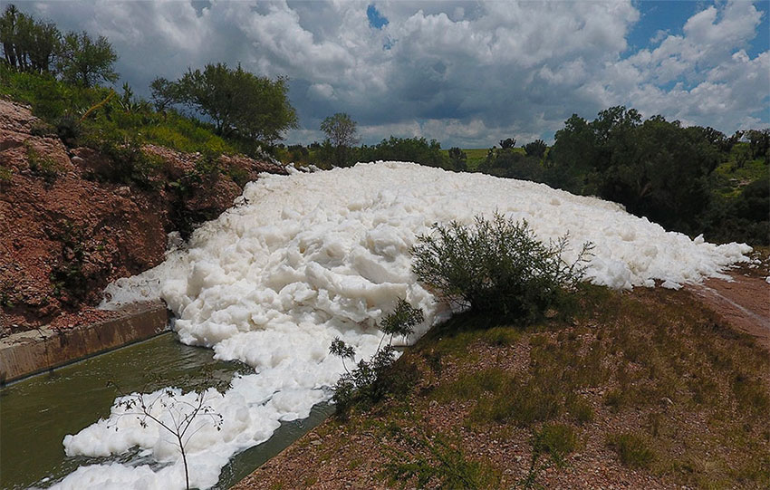 Foam overflows the canal's banks.