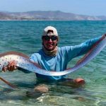 Jacob Thompson and the oarfish on a beach in Baja.