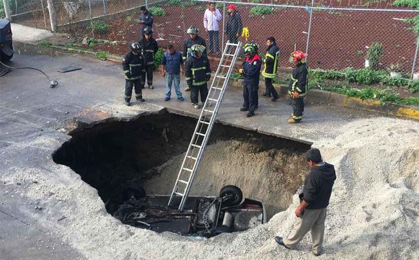 Emergency crews prepare to remove the second vehicle that fell in the large hole.