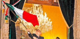 The president waves the flag Sunday night, watched by his wife, Beatriz Gutiérrez.