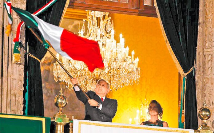 The president waves the flag Sunday night, watched by his wife, Beatriz Gutiérrez.
