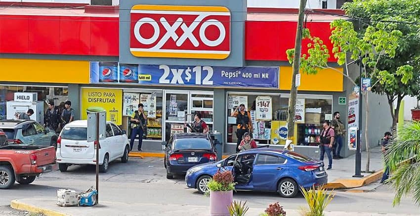 Armed gangsters stand watch outside an Oxxo store Thursday in Culiacán.