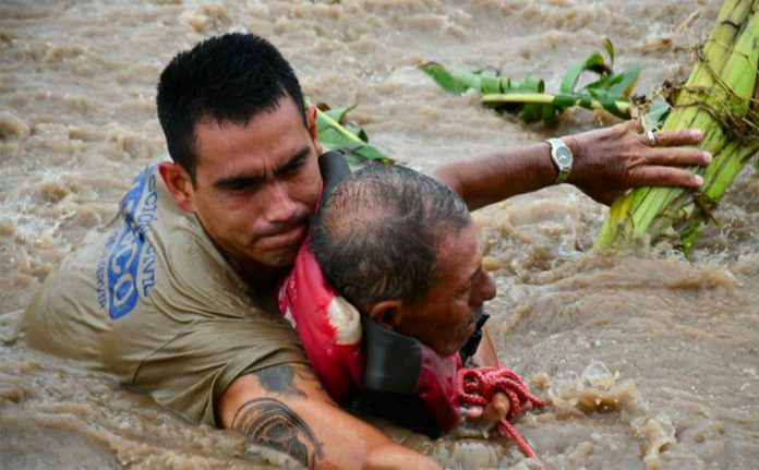 A rescue worker pulls a man out of floodwaters in Jalisco.